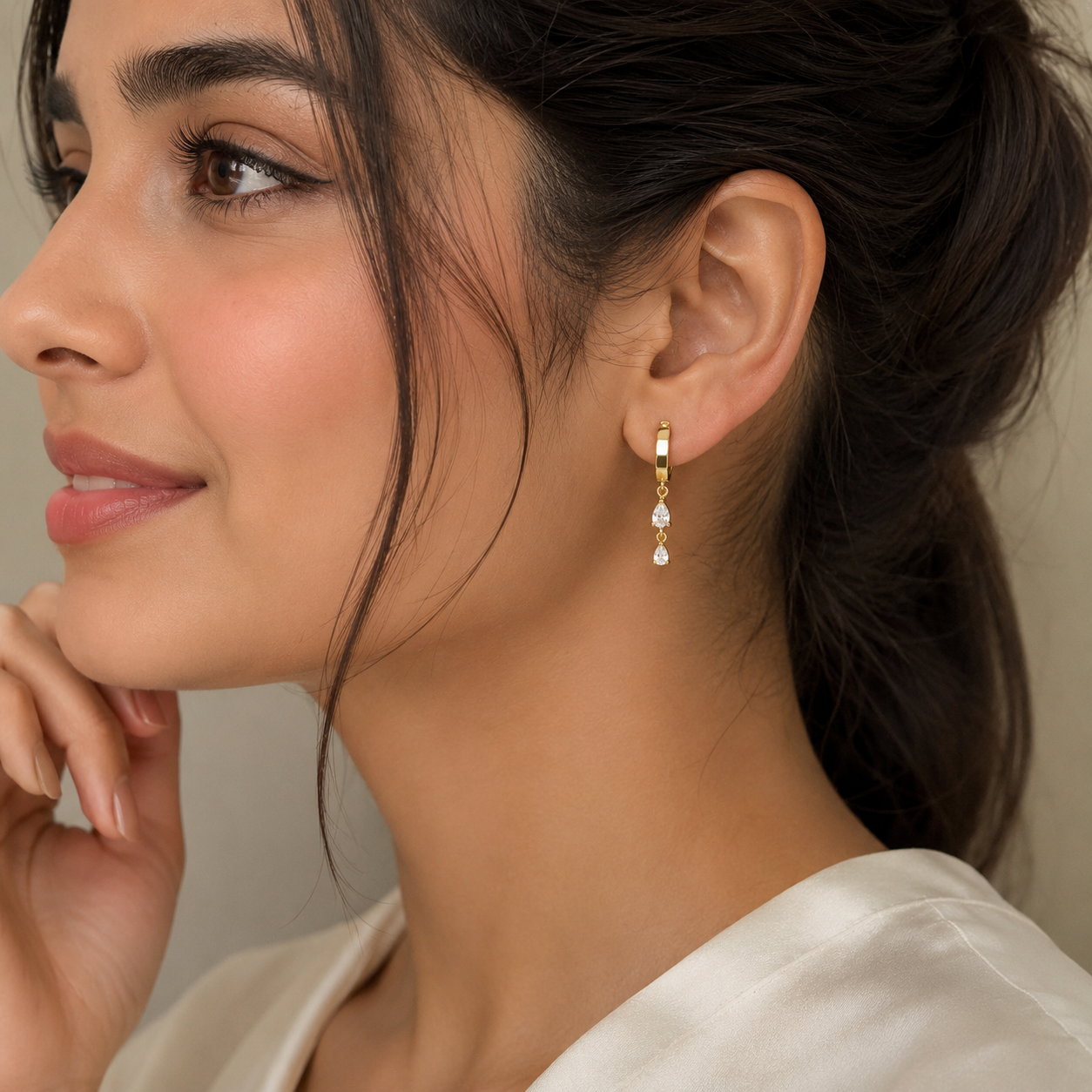 Close-up of a woman wearing gold earrings with a neutral background