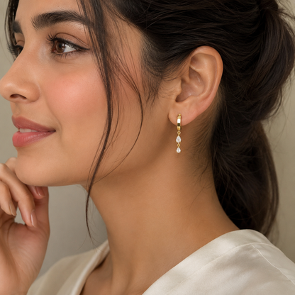 Close-up of a woman wearing gold earrings with a neutral background
