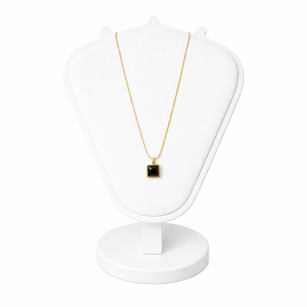 Necklace with a black pendant on a white stand against a white background
