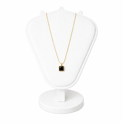 Necklace with a black pendant on a white stand against a white background