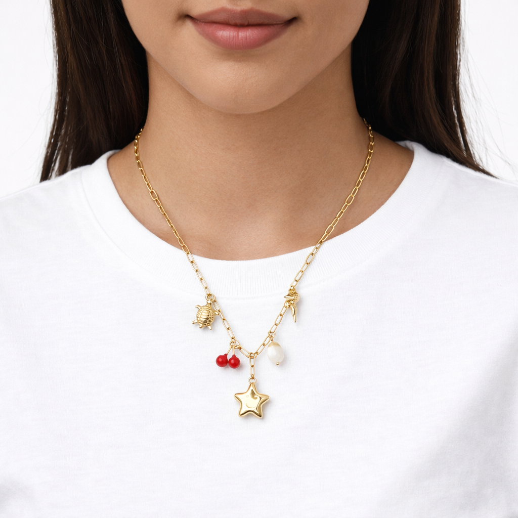 Gold necklace with star and red heart pendant worn by a person on a white background