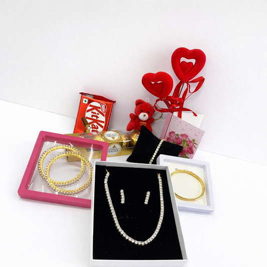 Jewelry set with gold bangles, pearl necklace, and earrings on a white background.