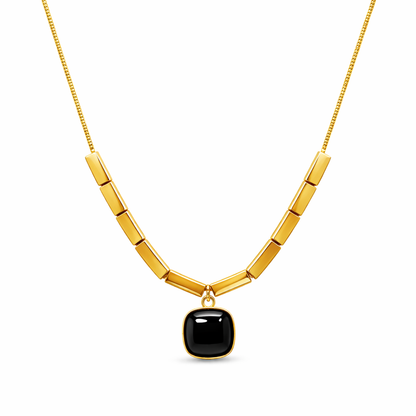 Gold necklace with a black pendant on a white background