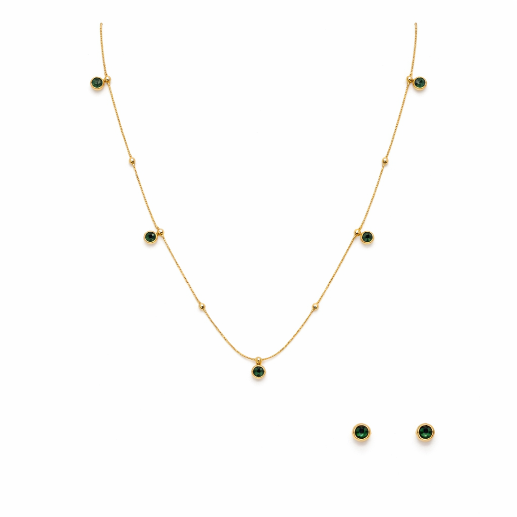 Gold necklace and earrings with green gemstones on a white background