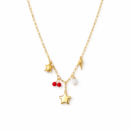 Gold necklace with star, red berry, and white pearl pendant on a white background