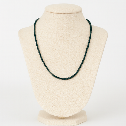 Green beaded necklace on a beige mannequin bust against a white background