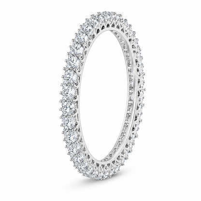 A diamond eternity ring in a polished silver-tone setting, featuring a continuous line of round-cut diamonds around the band, shown on a clean white background.
