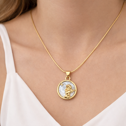 Gold necklace with a pendant on a person wearing a white top