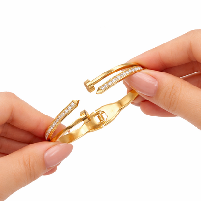 Gold bracelet with diamond accents held by a hand on a white background