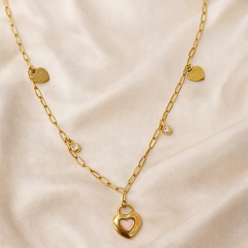 Gold necklace with a heart-shaped lock pendant on a beige fabric background