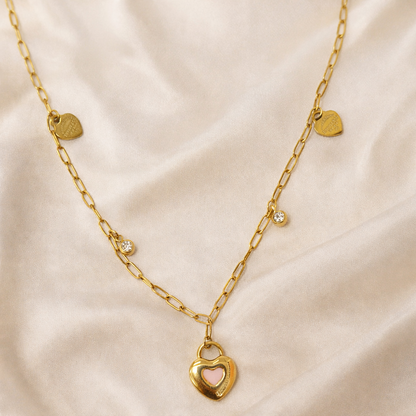 Gold necklace with a heart-shaped lock pendant on a beige fabric background