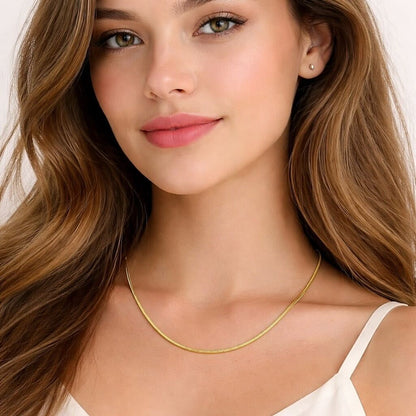 Woman wearing a gold necklace with a plain background
