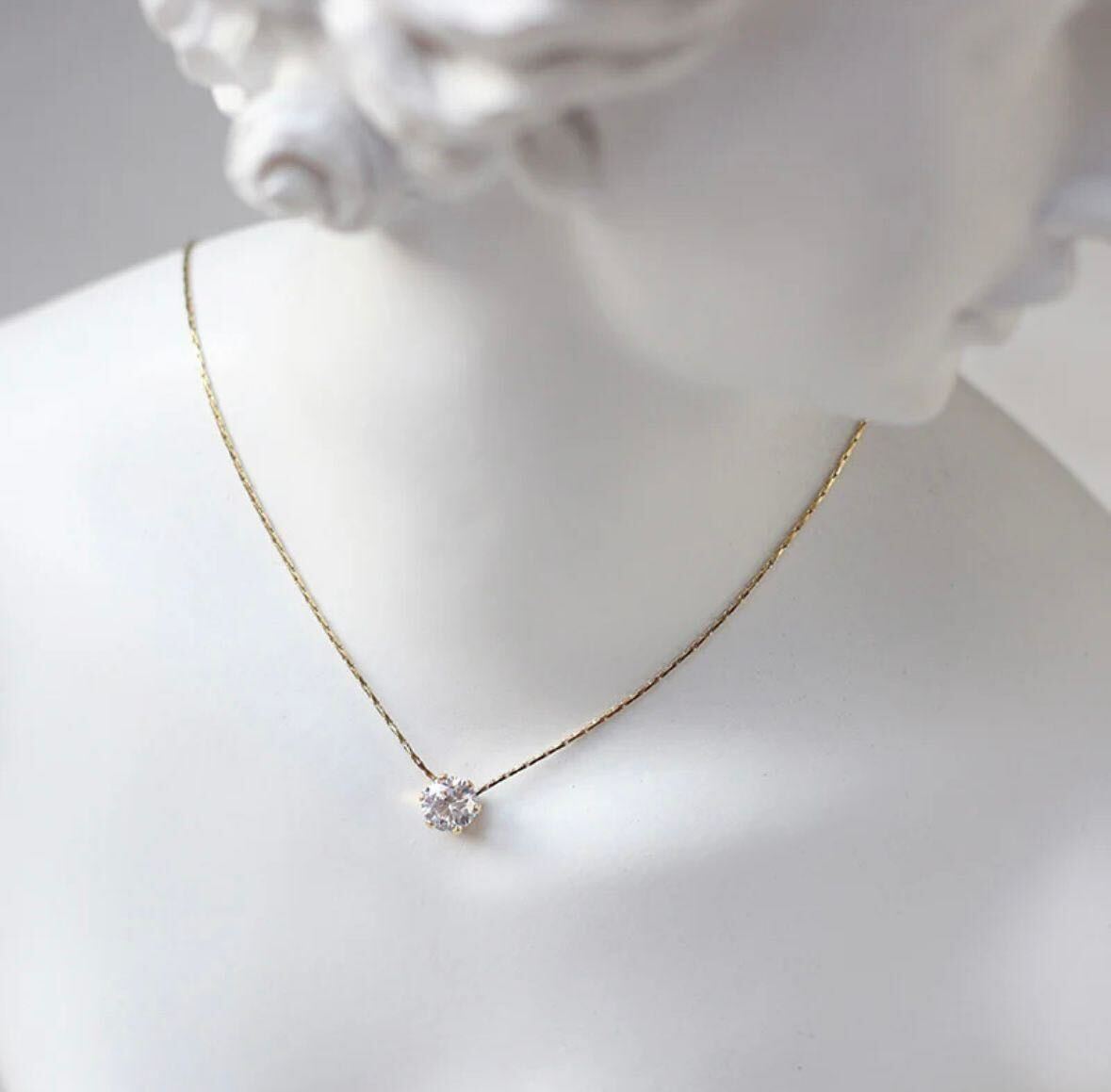 Gold necklace with a small pendant on a mannequin bust.
