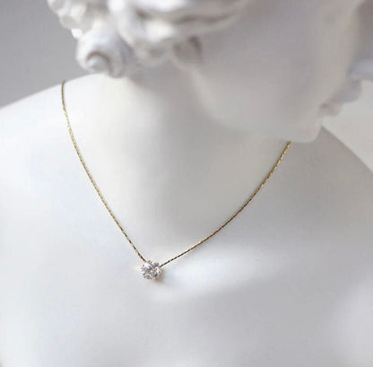 Gold necklace with a small pendant on a mannequin bust.