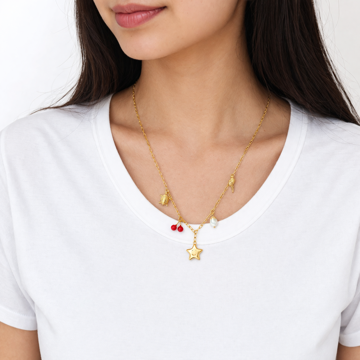 Gold necklace with star pendant worn by a person on a white background