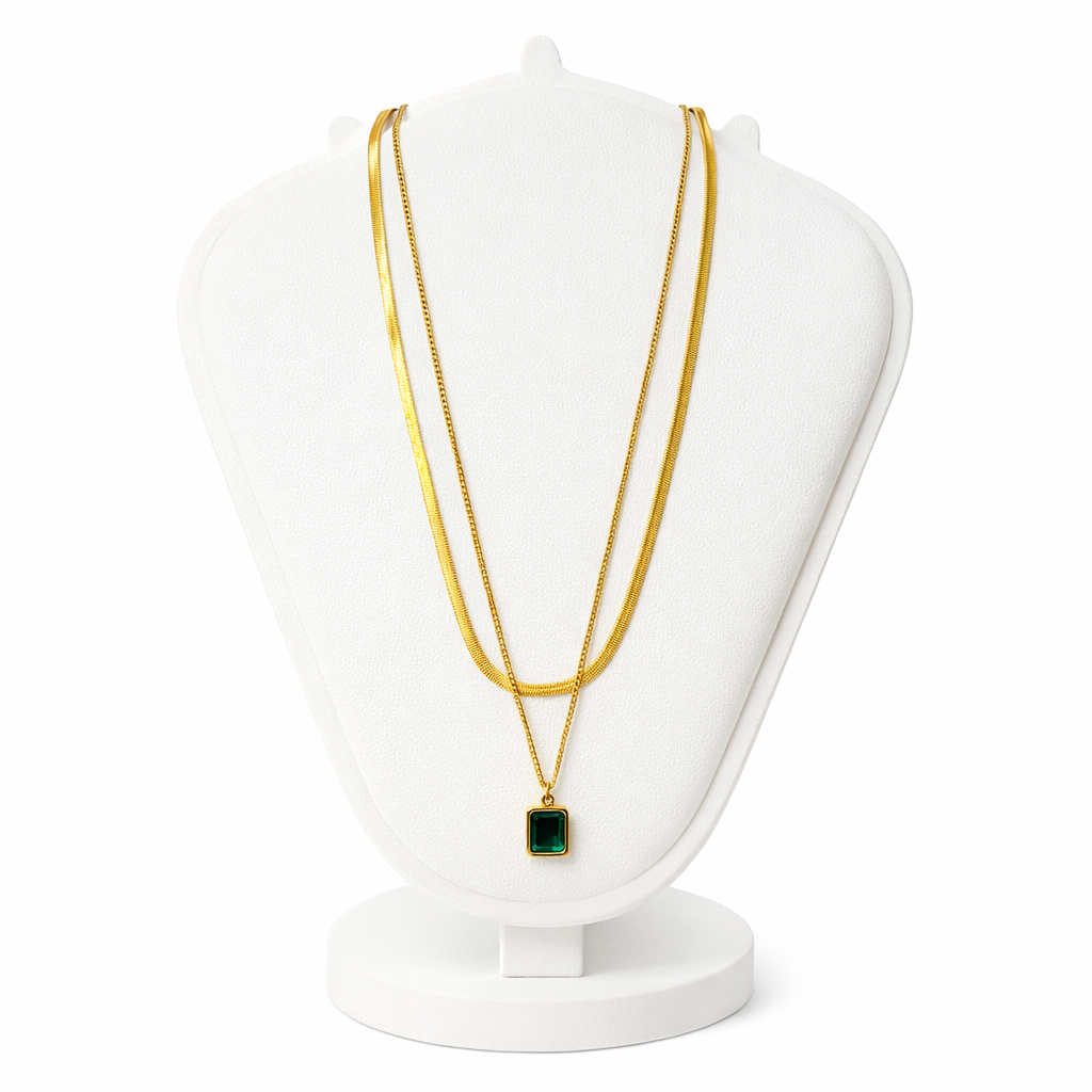 Gold necklace with a green pendant on a white mannequin bust