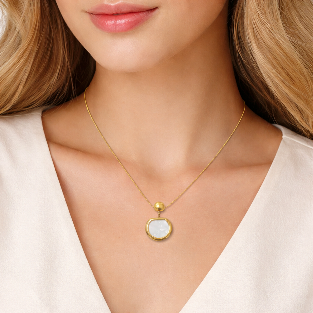 Gold necklace with a pendant worn by a model against a neutral background