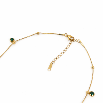 Gold anklet with green gemstones on a white background