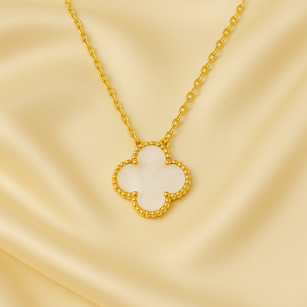 Gold necklace with a clover-shaped pendant on a beige background