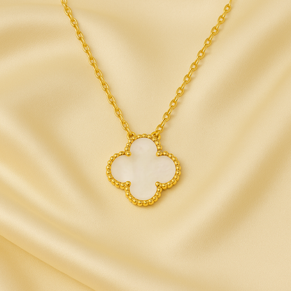 Gold necklace with a clover-shaped pendant on a beige background