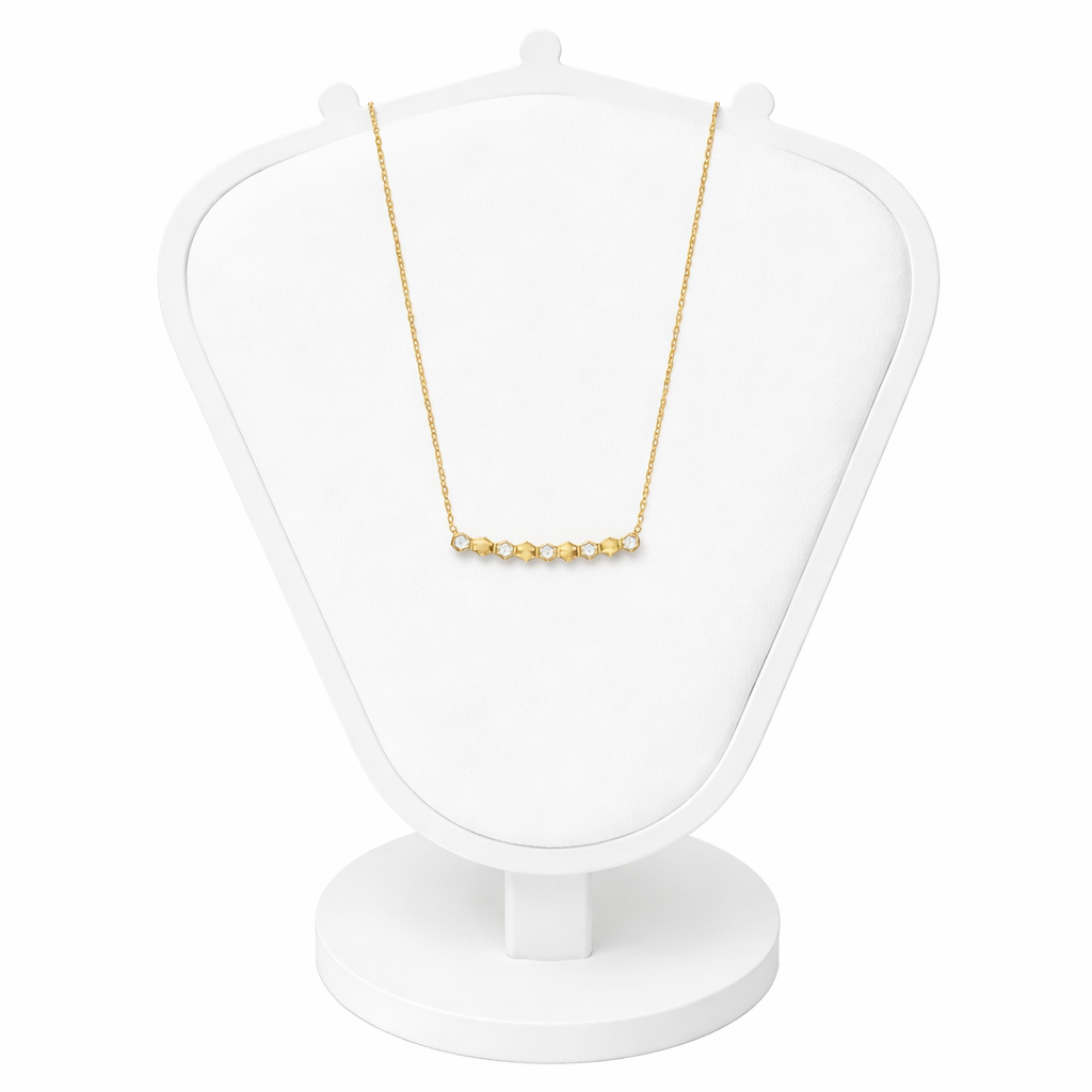 Gold necklace on a white jewelry display stand against a white background