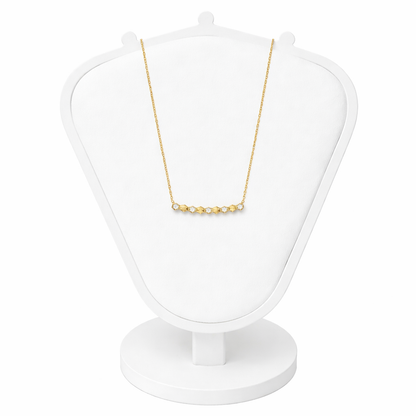 Gold necklace on a white jewelry display stand against a white background