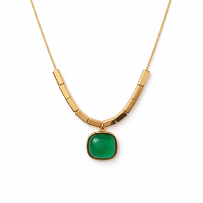 Gold necklace with a green pendant on a white background