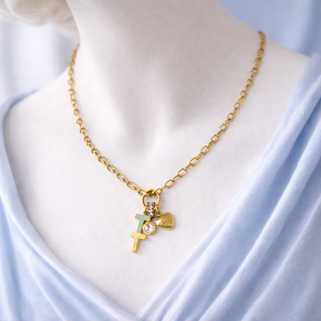 Gold necklace with heart and cross pendants on a mannequin against a light blue fabric background