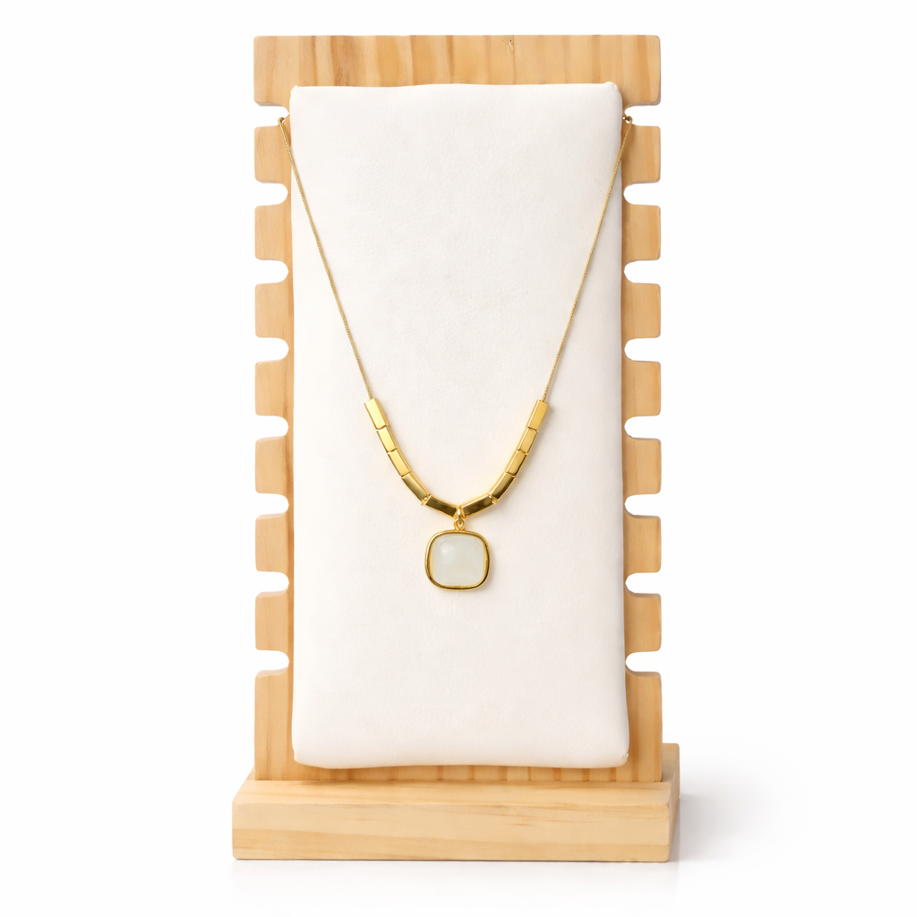 Gold necklace with a pendant on a wooden stand with a white background