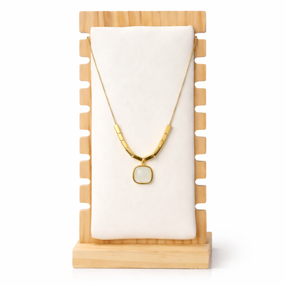 Gold necklace with a pendant on a wooden stand with a white background
