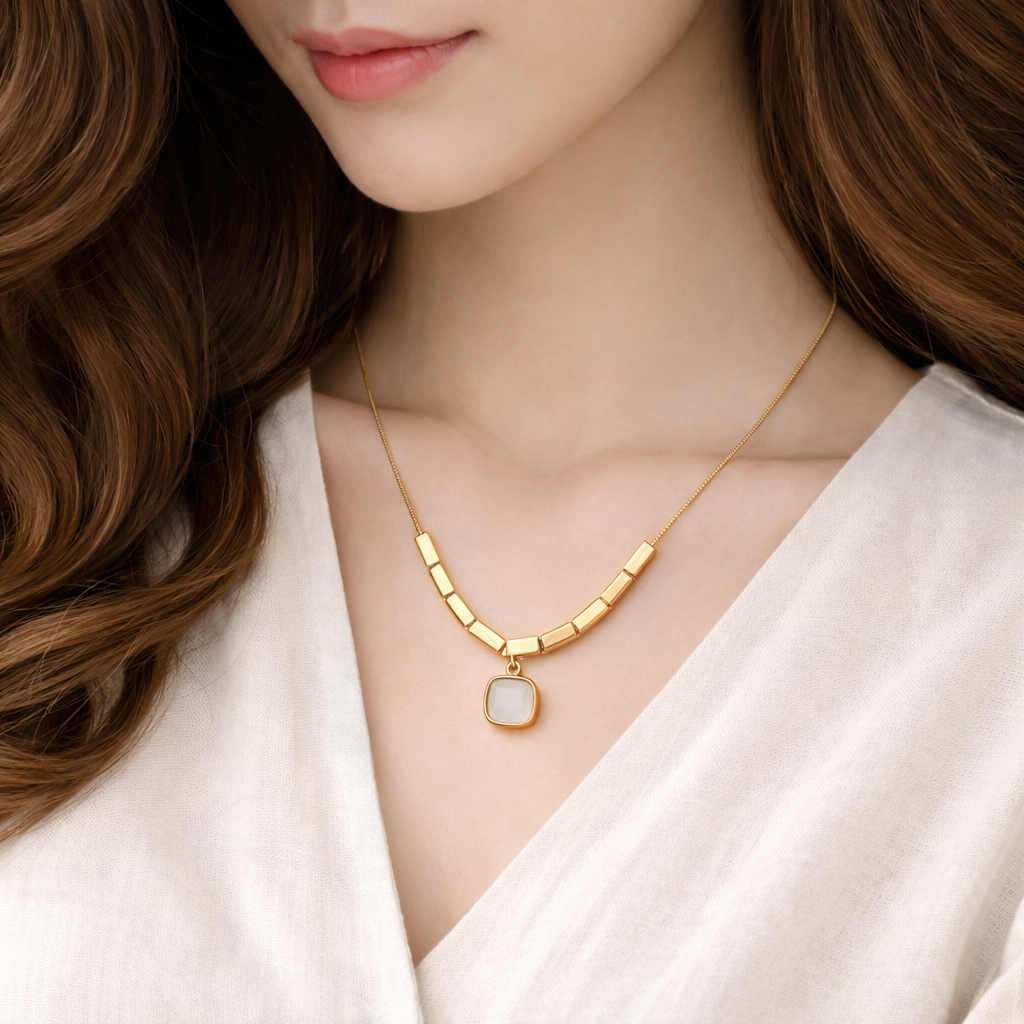 Gold necklace with a pendant on a model wearing a white top