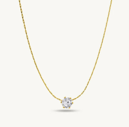 Gold necklace with a clear gemstone pendant on a white background