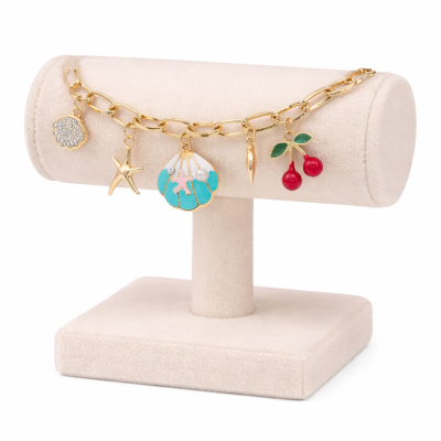 Jewelry bracelet with charms on a beige display stand against a white background