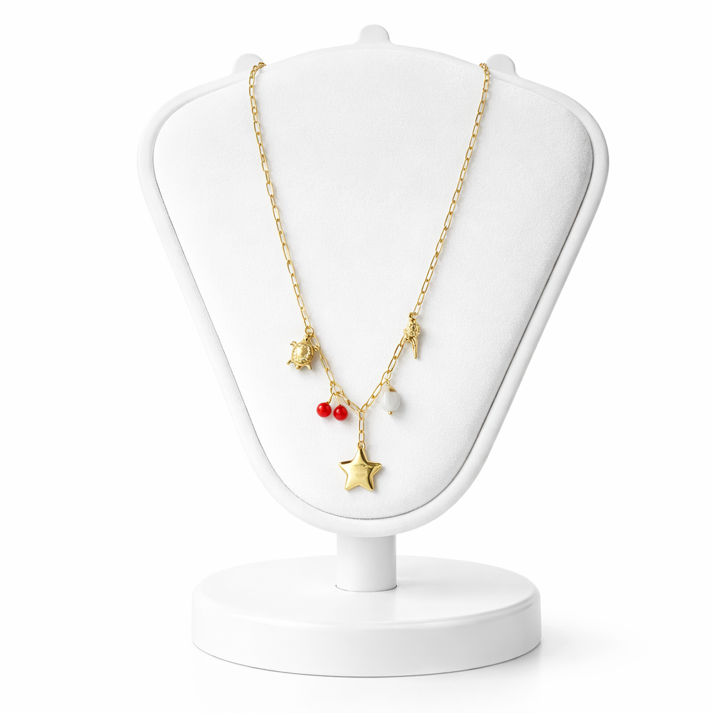 Gold necklace with star and red bead pendant on a white jewelry stand