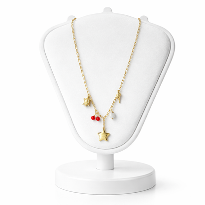 Gold necklace with star and red bead pendant on a white jewelry stand