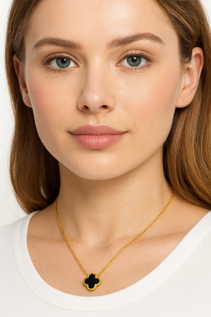 Woman wearing a gold necklace with a black pendant on a white background