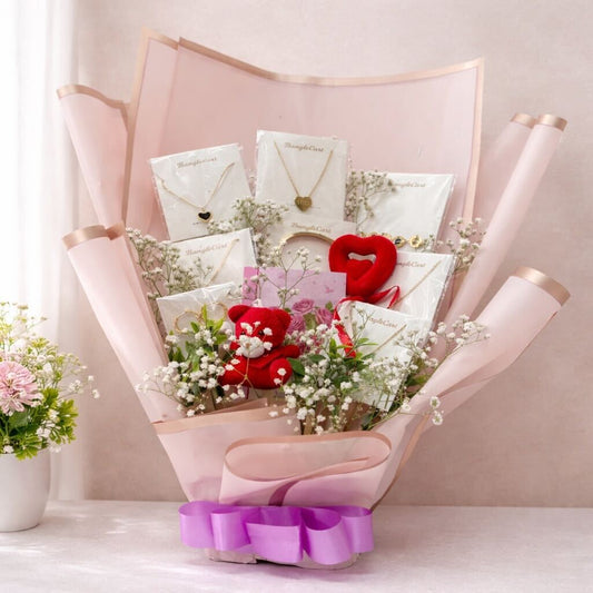 Bouquet of flowers with jewelry and a heart-shaped gift inside, against a light pink background.