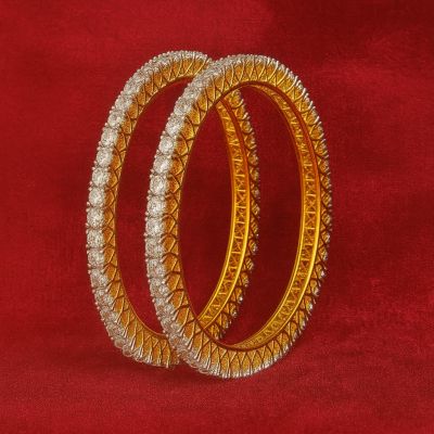 Pair of gold and diamond-studded bangles on a red background