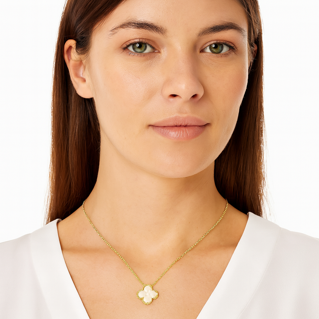 Woman wearing a gold necklace with a clover pendant on a white background