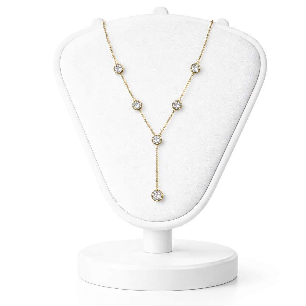 Gold necklace with clear stones on a white jewelry stand against a white background