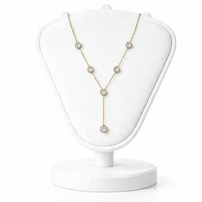 Gold necklace with clear stones on a white jewelry stand against a white background