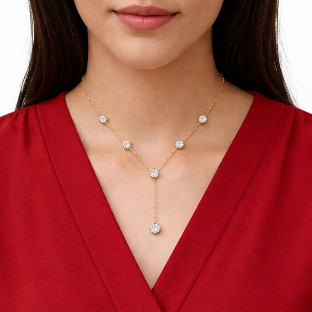 Woman wearing a gold necklace with gemstones against a white background