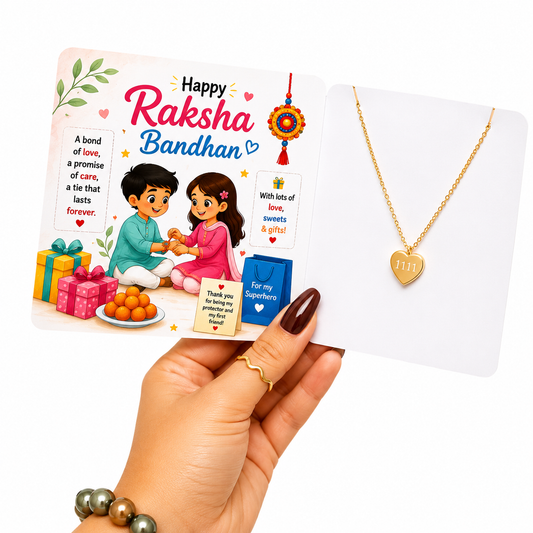 A hand holds a Raksha Bandhan gift card next to a gold heart-shaped necklace on a white display card. The card features festive illustrations of a boy and girl tying a cord with orange sweets and colorful presents, with the text 'Happy Raksha Bandhan'.