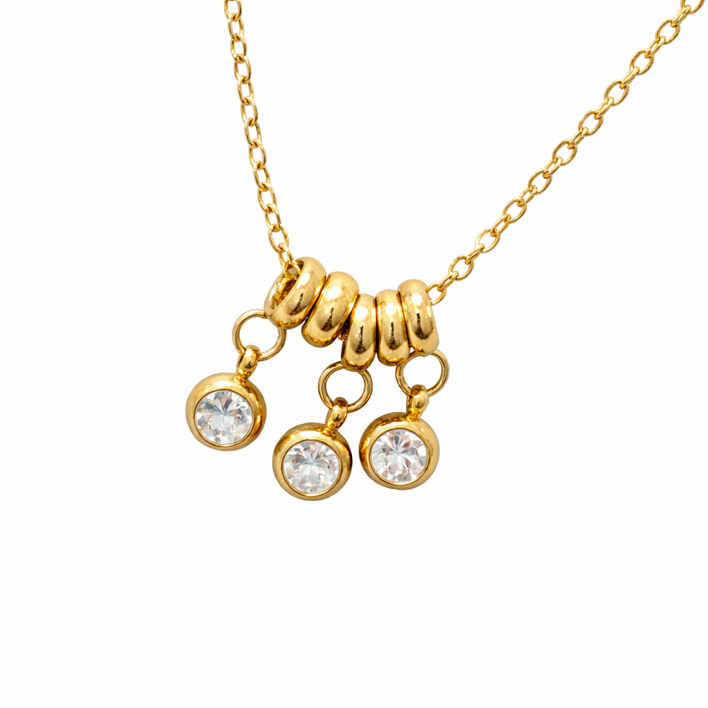 Gold necklace with three round pendants on a white background