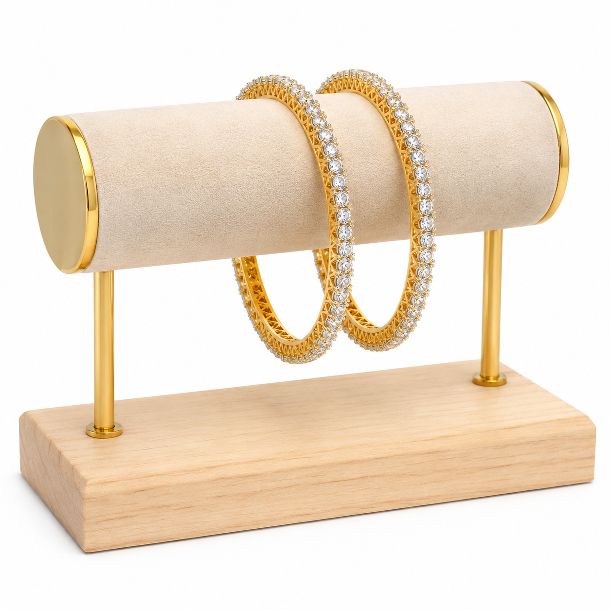 Two gold huggie bangles, one adorned with clear pavé stones and the other with small round stones, displayed on a gold and beige cylindrical jewelry stand with a wooden base against a white background.