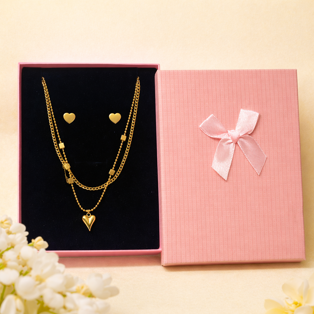 Gold heart-shaped jewelry set with pink gift box on a light background