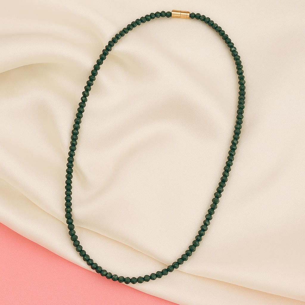 Green beaded necklace on a beige and pink fabric background

