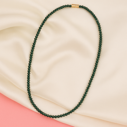 Green beaded necklace on a beige and pink fabric background

