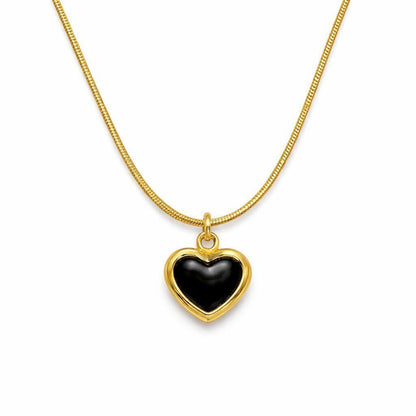 A gold heart pendant necklace with a smooth black center, suspended from a gold snake chain on a plain white background.
