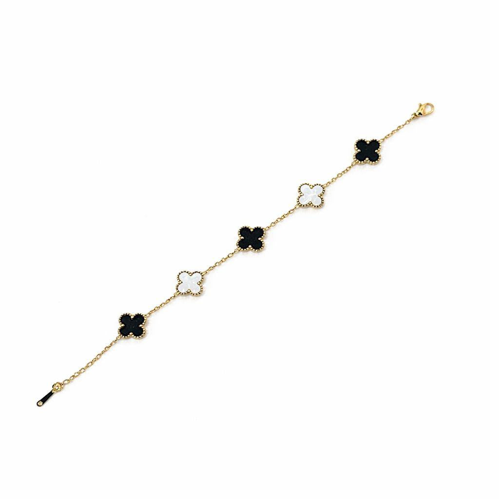Gold bracelet with black and white clover-shaped charms on a white background